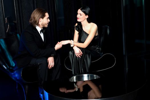 Elegant couple admiring each other, dark background.