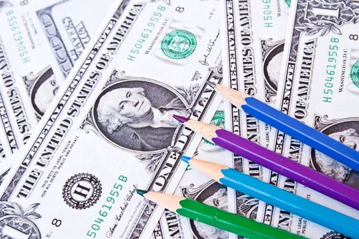 Colored pencils on a background of money