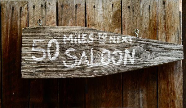 Wild West Rustic Wooden Sign Pointing To Next Saloon
