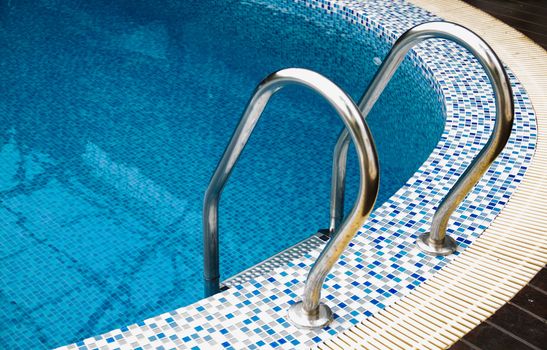 Grab bars ladder in blue swimming pool