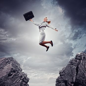 Image of young businesswoman jumping over gap