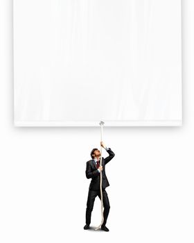 Image of young businessman pulling blank banner. Place for text