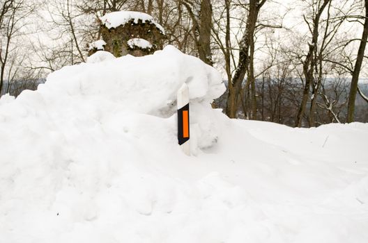 light reflector pillar hidden in huge pile of snow on road side in north winter.