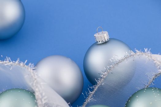 Glass Christmas balls with holiday ribbon on blue background