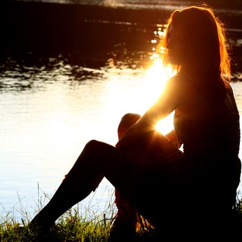 Girl sitting on tha bank of forest river