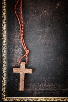 Closeup of simple wooden Christian cross necklace on holy Bible with copy space