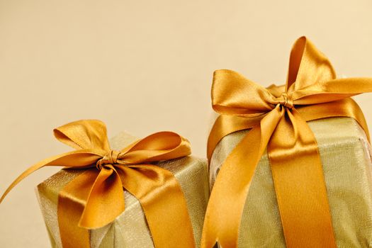 Two gift boxes wrapped in gold ribbons with copy space