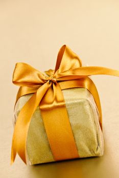 Gift box in gold wrapping paper with ribbon and bow