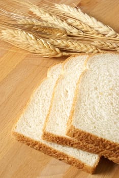 A closeup of some fresh baked bread that has been sliced on a wooden board.