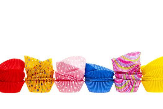 Several stacks of colorful muffin or cupcake cups isolated on white background as border