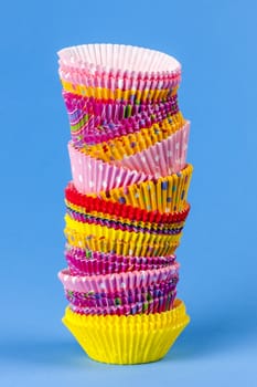 Tall stack of colorful muffin or cupcake cups on blue background
