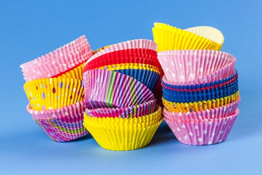 Several stacks of colorful muffin or cupcake cups on blue background