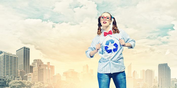 Young woman acting like super hero with recycle sign on chest