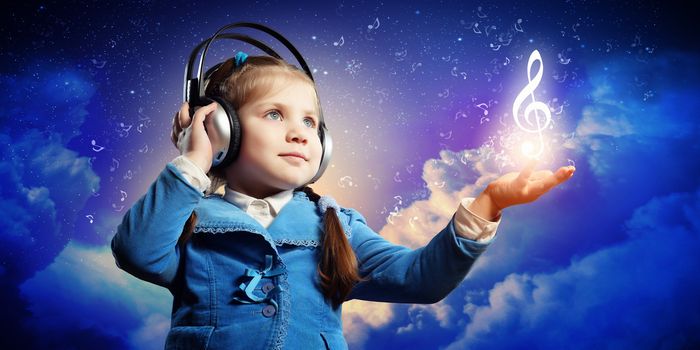 Little cute girl in headphones enjoying music