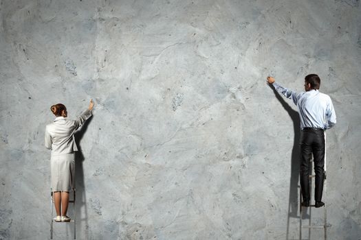 businesspeople standing on ladder drawing diagrams and graphs on wall