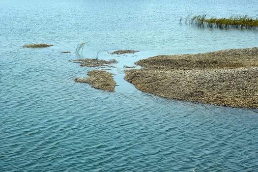 Heap of pebbles in a shallow marine lagoon in a lovely summer day