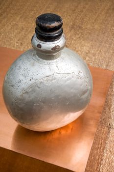 Vertical color portrait in a studio showroom interior displaying old industrial aluminum chemical bottle standing on a copper plated occasional table. Generic shot location was Bombay India, available with property release.