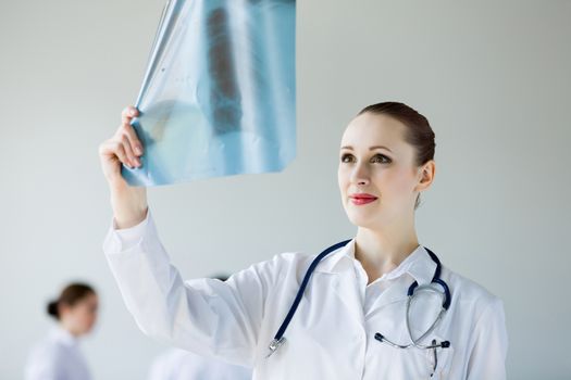 Attractive young female doctor examining x-ray results