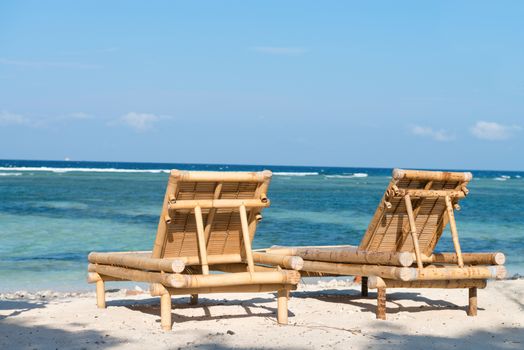 Tropical seascape with bamboo beach beds under blue sky