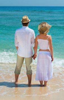Back view on couple enjoying at beach and looking on the blue sea