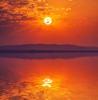 Vibrant rising sun at dawn over water, beautiful scenery