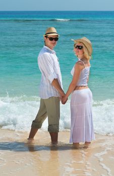 Happy young couple in sunglasses enjoying at beach with blue sea on background
