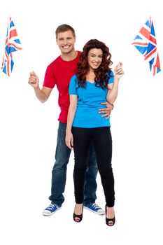 Guy hugging his girlfriend and both holding UK flag isolated over white background