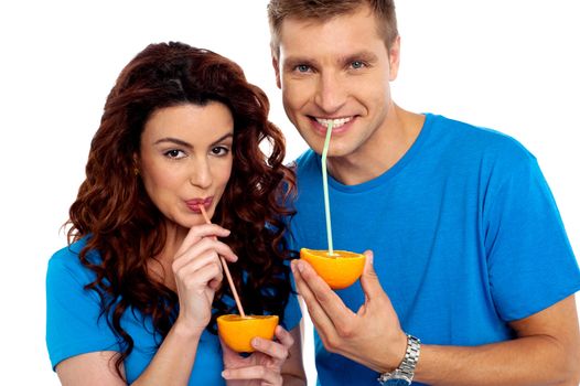 Closeup of couple cuddling and sipping orange juice. Smiling at camera