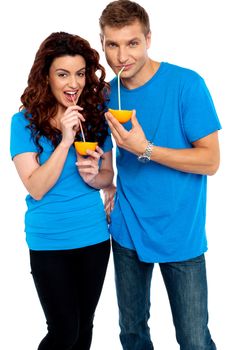 Young couple drinking orange juice together, sipping with straw