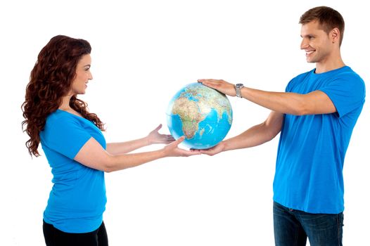 Causal young couple holding globe together and looking at each other