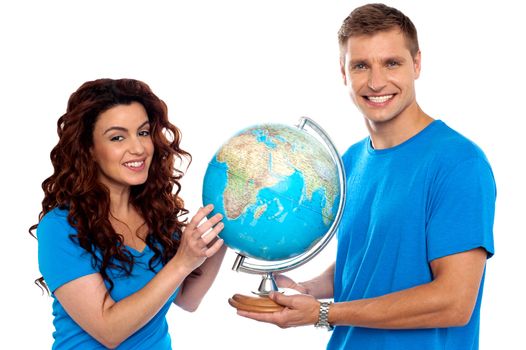 Joyful couple holding globe and smiling at camera. Isolated over white background
