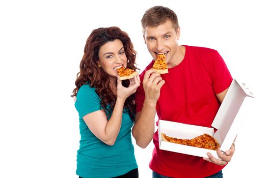 Adorable young couple relishing yummy pizza. Indoor studio shot