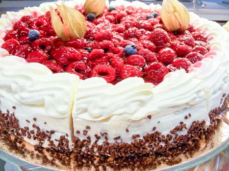 Closeup of a cream cake covered with raspberries and gelatin