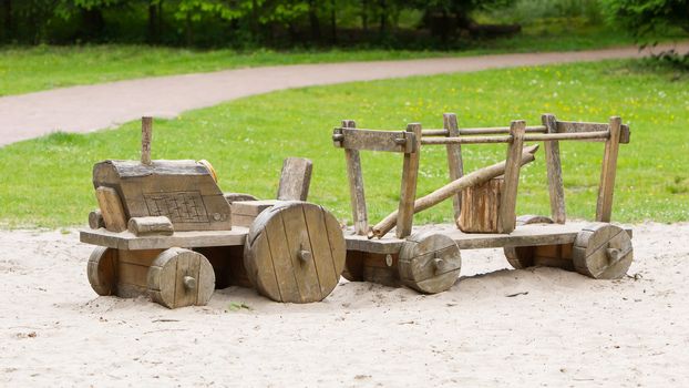 Wooden toy tractor with trailer in the sand