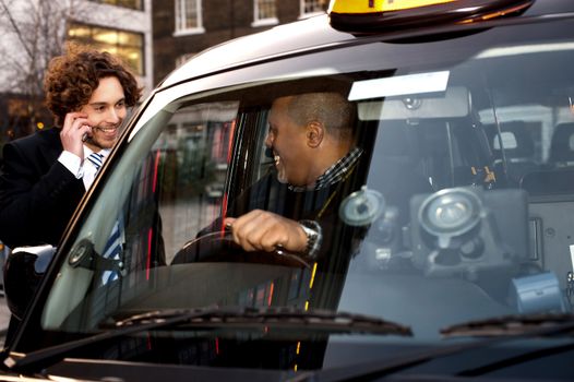 Taxi cab driver communicating with male passenger.