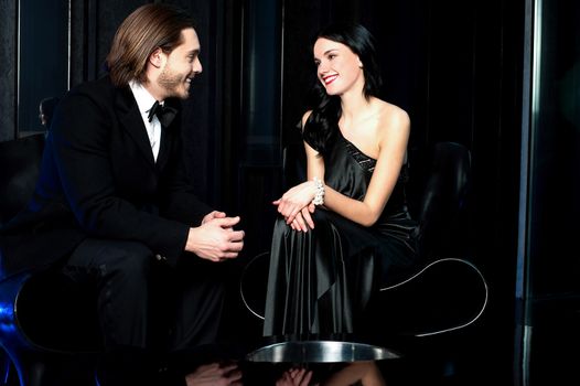 Elegant couple admiring each other, dark background.