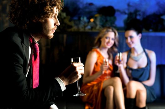 Charming beautiful girls looking at handsome young guy in a bar.