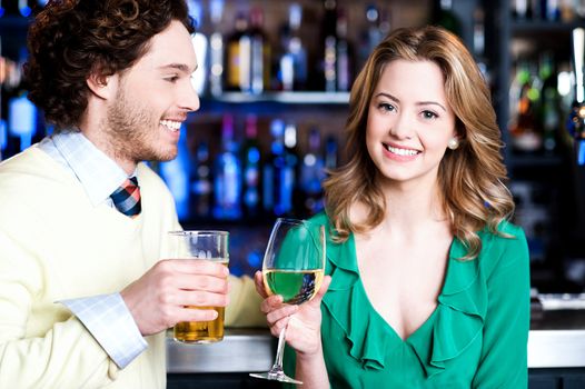 Cheerful young couple having cocktail at restaurant bar.