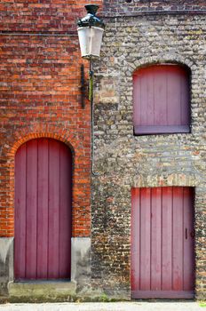 Detail of old vintage brick wall with red wooden doors and windows