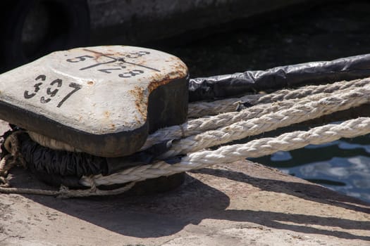 Ropes tied on a ship deck with boats at marina