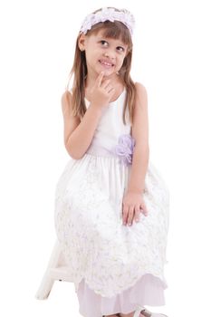 little girl wearing white dress and posing on chair on white background