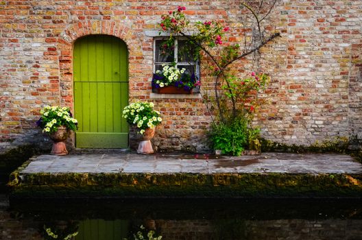 Vintage old wall with greed door and flowers, Bruges, Belgium