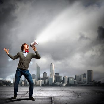 Portrait of young man shouting loudly using megaphone