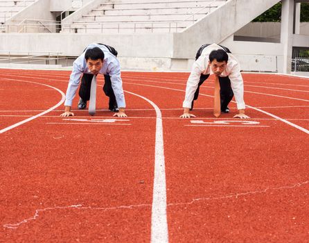 Two same business men get ready on start line of the runway to have competition