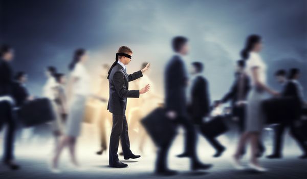 Image of businessman in blindfold walking among group of people