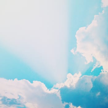 Dramatic blue sky with clouds and sunbeams, retro filter effect