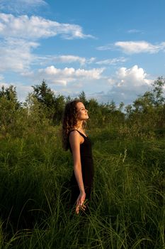 Beautiful girl walks and dreams in high grass on the banks of river