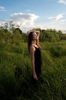 Beautiful girl walks and dreams in high grass on the banks of river