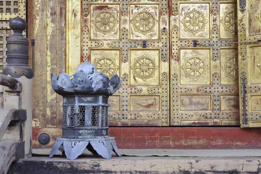 traditional copper lantern close to scenic doors of oriental Buddhist temple