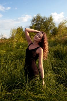 Beautiful girl walks and dreams in high grass on the banks of river